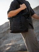 Person holding a black backpack against a mountainous background