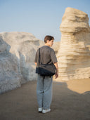 Person standing in a desert landscape with large rock formations.